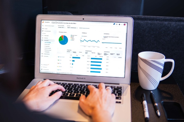 Google Analytics and Google Ads dashboard on laptop along with a mug and pens.