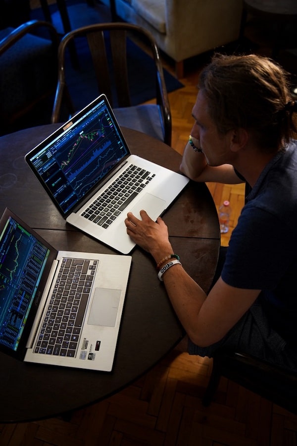 Man sitting and using 2 laptops for keyword research of a business.